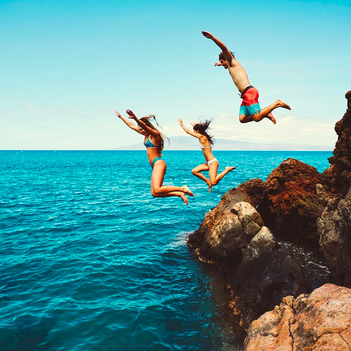 This is an image of three staff jumping into the sea