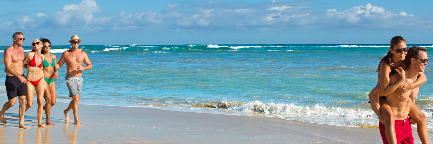 This is an image of 3 couples walking happily on the beach