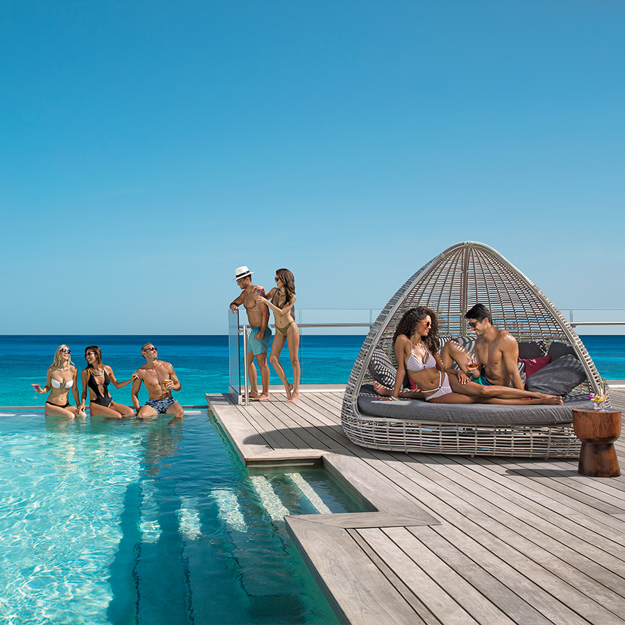 This is an image of people enjoying a sunny day in the pool with an ocean view