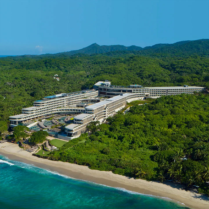 this is an aerial image of a secrets all-inclusive resorts Mexico Resort in the mountains with a crystal clear beach by Inclusive Collection